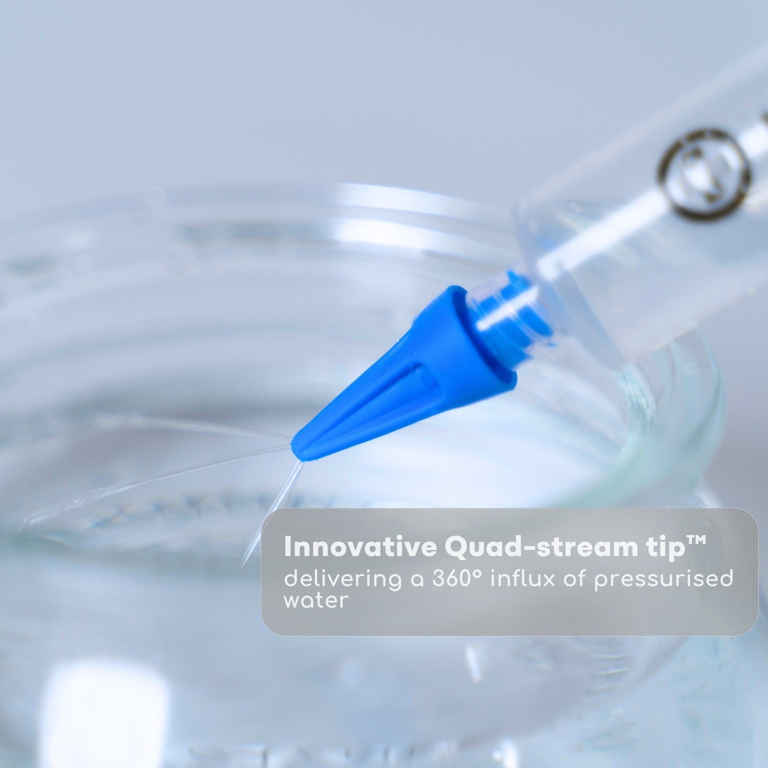 Blue quad-stream tip delivering pressurized water with a blurred background