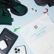Load image into Gallery viewer, Flat lay of vomit bag, sleeping eye mask, 2 ear plugs, beside a passport and mobile phone