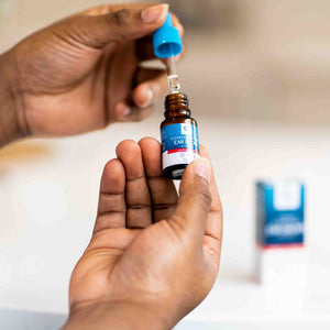 Close up of Sodium Bicarbonate Ear Drops held by a hand with the retail box in the background