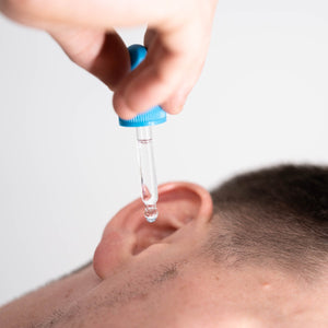 A man using ear drops on his ear