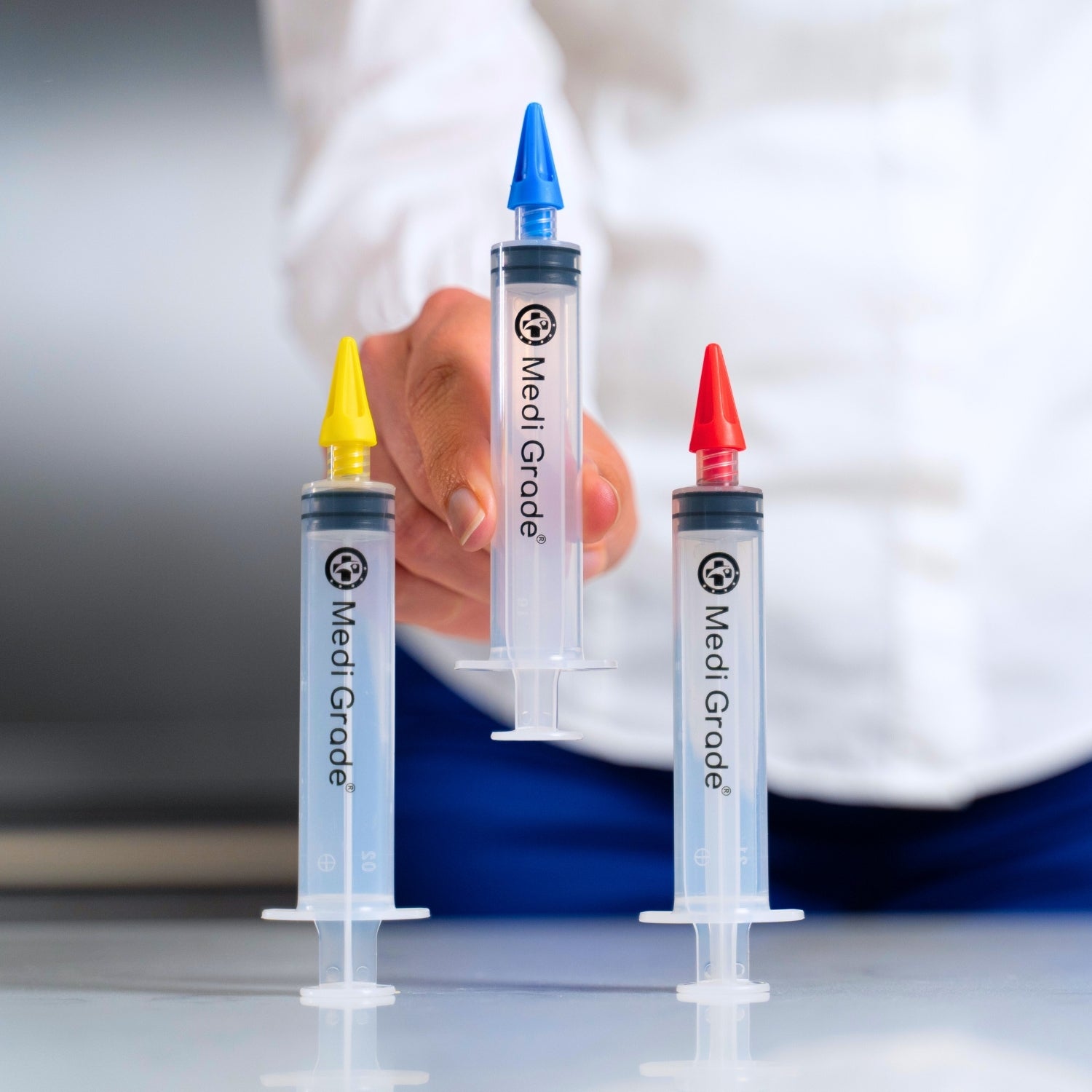 Three Medi Grade syringes with color-coded caps on a white surface.