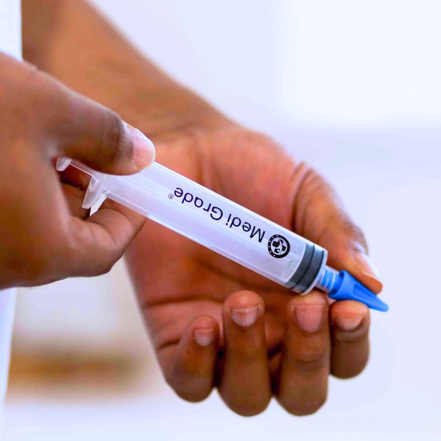 Hand holding a Medi Grade syringe with a blurred background