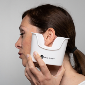 A woman holding an ear basin below her ear